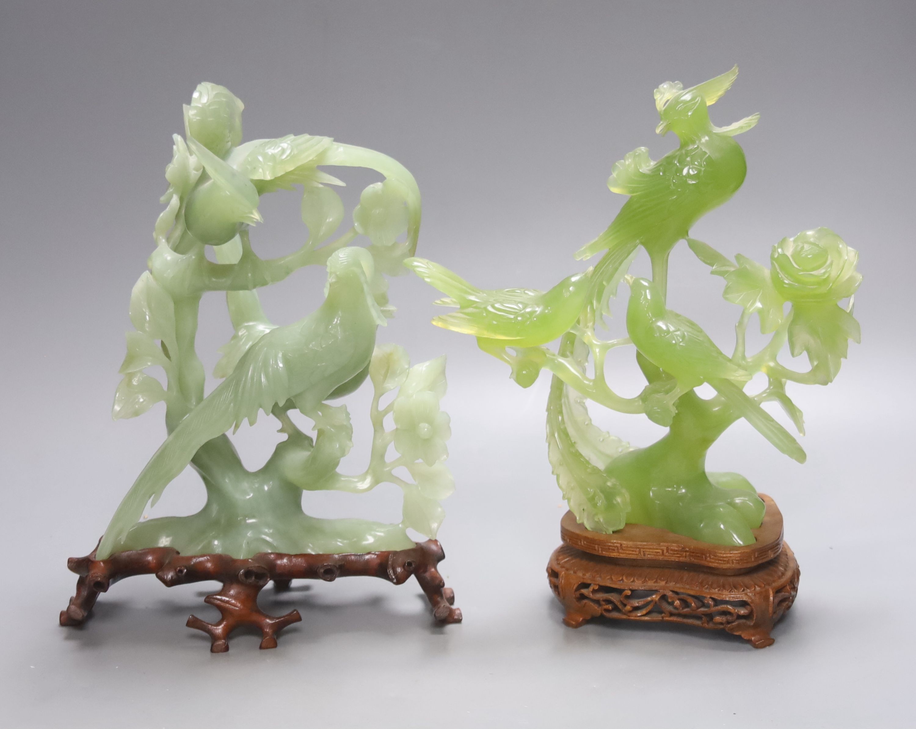 Two Chinese green bowenite jade carvings of exotic birds, H 28cm with carved wooden stands